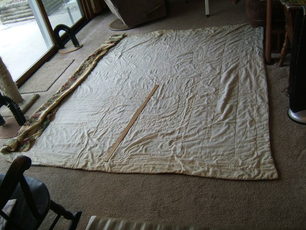 Old dirty quilt on floor, with yardstick