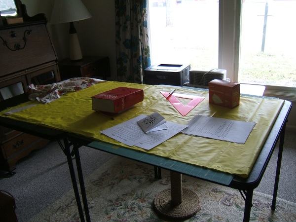 two card tables with Christmas cards in 
                     progress on top of windbreaker in progress