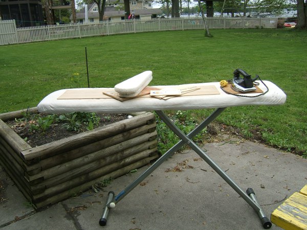 ironing board on patio, with leg board, sleeve board, iron, and other bits of plywood