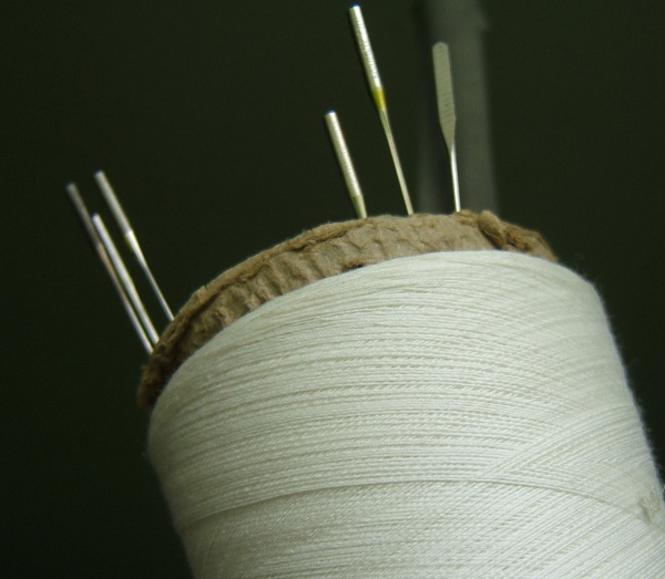 Old machine needles stuck into base of thread cone